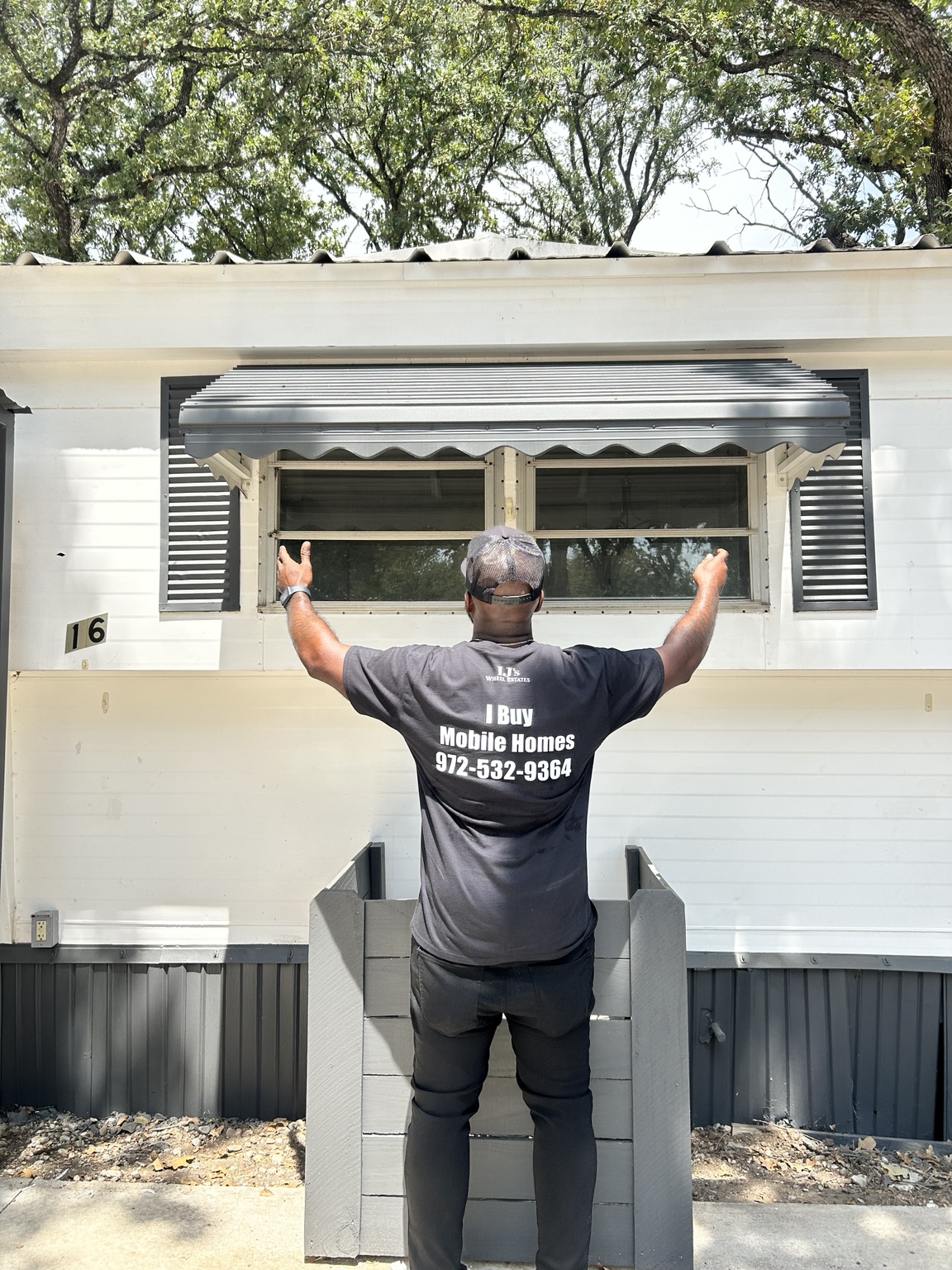 IJ’s Wheel Estates founder wearing an I Buy Mobile Homes shirt in front of a manufactured home